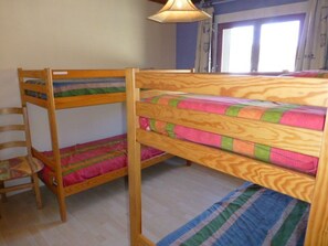 A bunk bed room with a wooden frame, a chair, and a window with curtains. - Cozy 3P6P apartment near slopes in L'Alpe d'Huez (Huez)