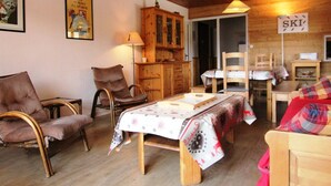 A cozy room with wooden furniture, a dining table, and a sign indicating a ski area.
