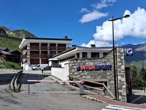 A building with a sign reading 'INTERSPORT' and a stone wall with a mailbox.