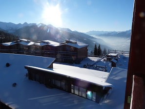 Estância de esqui com montanhas cobertas de neve, edifícios e teleféricos.