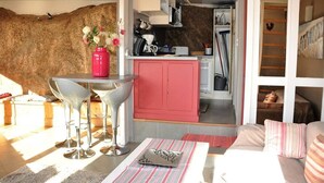 A compact living space with a kitchenette, a dining area with bar stools, and a cozy seating area with a sofa and cushions. - Architect-designed house in Ploumanac'h with stunning sea view (Perros-Guirec)