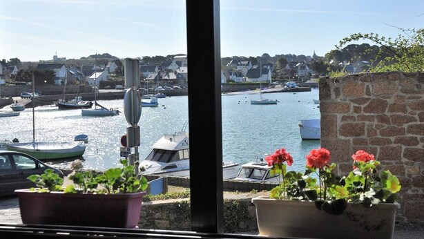 A view from a window overlooking a harbor with boats, a stone wall, and potted plants. - Architect-designed house in Ploumanac'h with stunning sea view (Perros-Guirec)