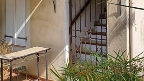 A building with a staircase, a door with shutters, and a table with chairs outside. - Leï Bugadiero - LA CROIX VALMER (La Croix-Valmer)