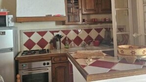 A kitchen with wooden cabinets, a gas stove, a built-in oven, and a hanging light fixture. - Leï Bugadiero - LA CROIX VALMER (La Croix-Valmer)