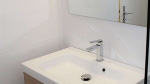Un baño moderno con un lavamanos blanco, grifo cromado y un espejo encima.