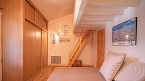 A bedroom with a wooden bed, a wooden staircase, and a poster on the wall. - Spacious apartment in Valmorel, 11 beds, 4 rooms, ski locker (Valmorel)