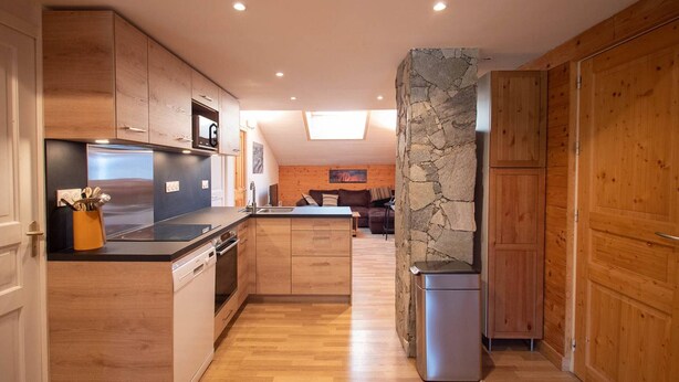 A modern kitchen with wooden cabinets, a central island, and a stone accent wall. - Spacious apartment in Valmorel, 11 beds, 4 rooms, ski locker (Valmorel)