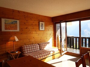 Relax in a serene room with a sofa, table, and lamp, offering a view of the surrounding mountains.