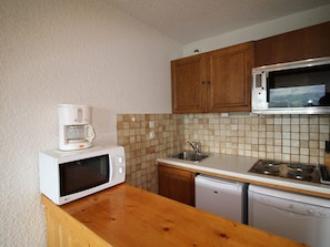 Efficient kitchen with microwave, coffee maker, sink, and dishwasher.