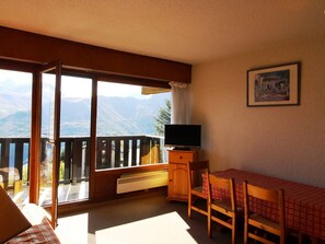 Enjoy a scenic mountain view from the balcony, featuring a comfortable seating area and a warm atmosphere.