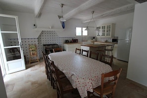 Une cuisine spacieuse avec un coin repas, des meubles blancs et un dosseret carrelé.