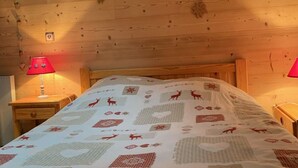 Une chambre dans un chalet en bois, avec un lit, deux tables de chevet et une lampe rouge de chaque côté.