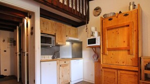 Une cuisine compacte avec des meubles en bois, un four à micro-ondes, un évier et un réfrigérateur.