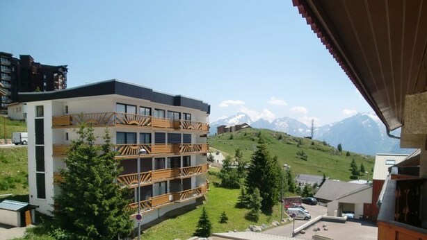 Un hôtel à plusieurs étages, doté de balcons, d  ’un parking et offrant une vue sur un paysage montagneux.