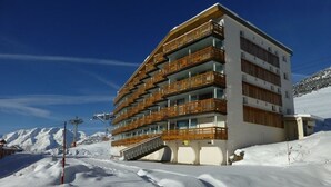 A multi-story hotel with wooden balconies, located in a snowy mountainous area. - Cozy studio for 4 in L'Alpe d'Huez, near slopes, pets welcome (Huez)