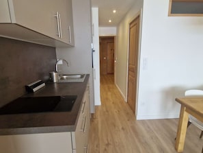 Una cocina moderna con un lavamanos integrado, una pequeña encimera y suelo de madera.