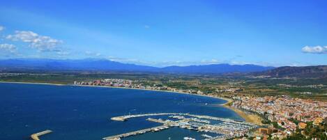 A coastal town with a marina, residential buildings, and a mountainous backdrop.