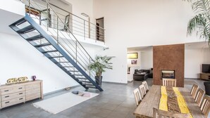 Amplia sala de estar con escalera, mesa de comedor y sofá.
