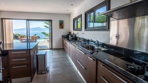 Una cocina moderna con una isla grande, electrodomésticos de acero inoxidable y vistas al océano.