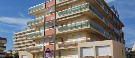 Un edificio residencial de varios pisos con balcones, una señal de no estacionamiento y un paso de peatones.