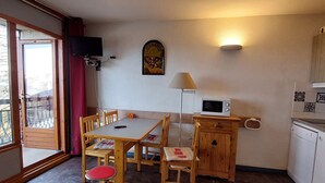 Una cocina compacta con mesa, sillas, microondas y un mueble pequeño.