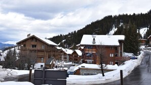 Un villaggio montano innevato con edifici in legno e una strada.