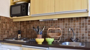 Una cucina con mobili in legno, un forno a microonde, un lavandino e un espositore per piatti.