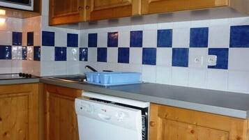 Een koelkast, een oven, een vaatwasser, kookgerei, borden en bestek