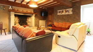Un salon confortable avec une cheminée, un canapé, un fauteuil et un téléviseur.