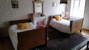 Une pièce avec deux lits en bois, un miroir, un radiateur et une fenêtre.