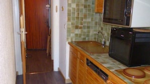 Eine kleine Küche mit Holzschränken, einer Mikrowelle, einem Spülbecken und einem Geschirrspüler.