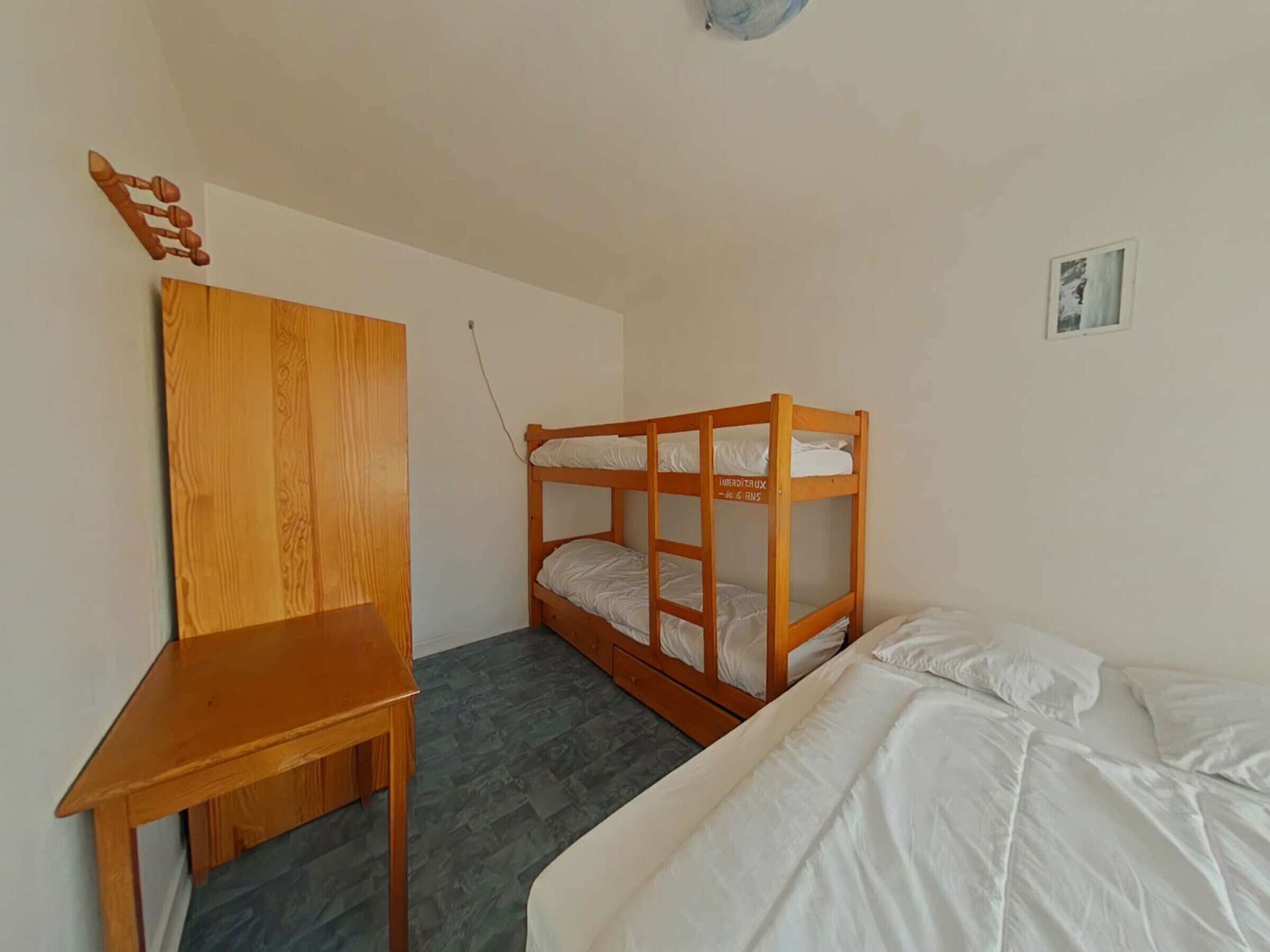 Une petite pièce avec un lit superposé, un bureau en bois et une chaise.