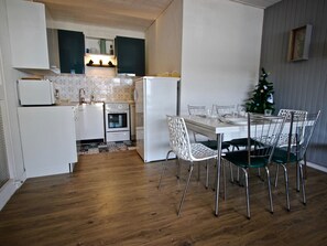 A compact kitchen with white appliances, a dining area with a white table and chairs, and a small Christmas tree.
