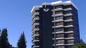 Een hoog, modern gebouw met meerdere balkons en een plat dak.