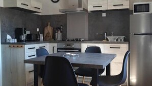 Une cuisine moderne avec une table et des chaises, un réfrigérateur et une horloge au mur.