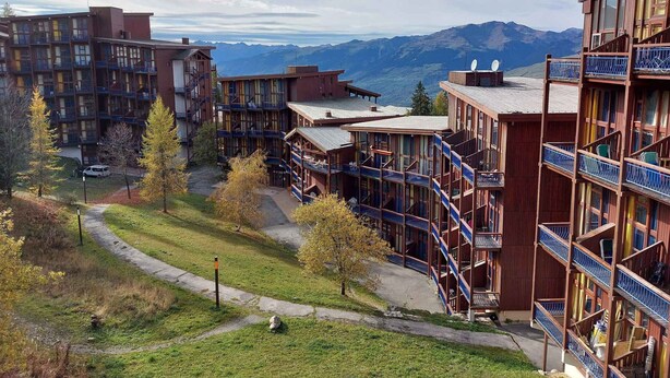Um resort moderno com vários edifícios, varandas e vista para as montanhas.