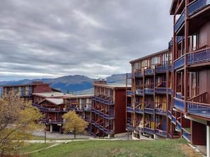 Un hotel a più piani con balconi e montagne sullo sfondo.