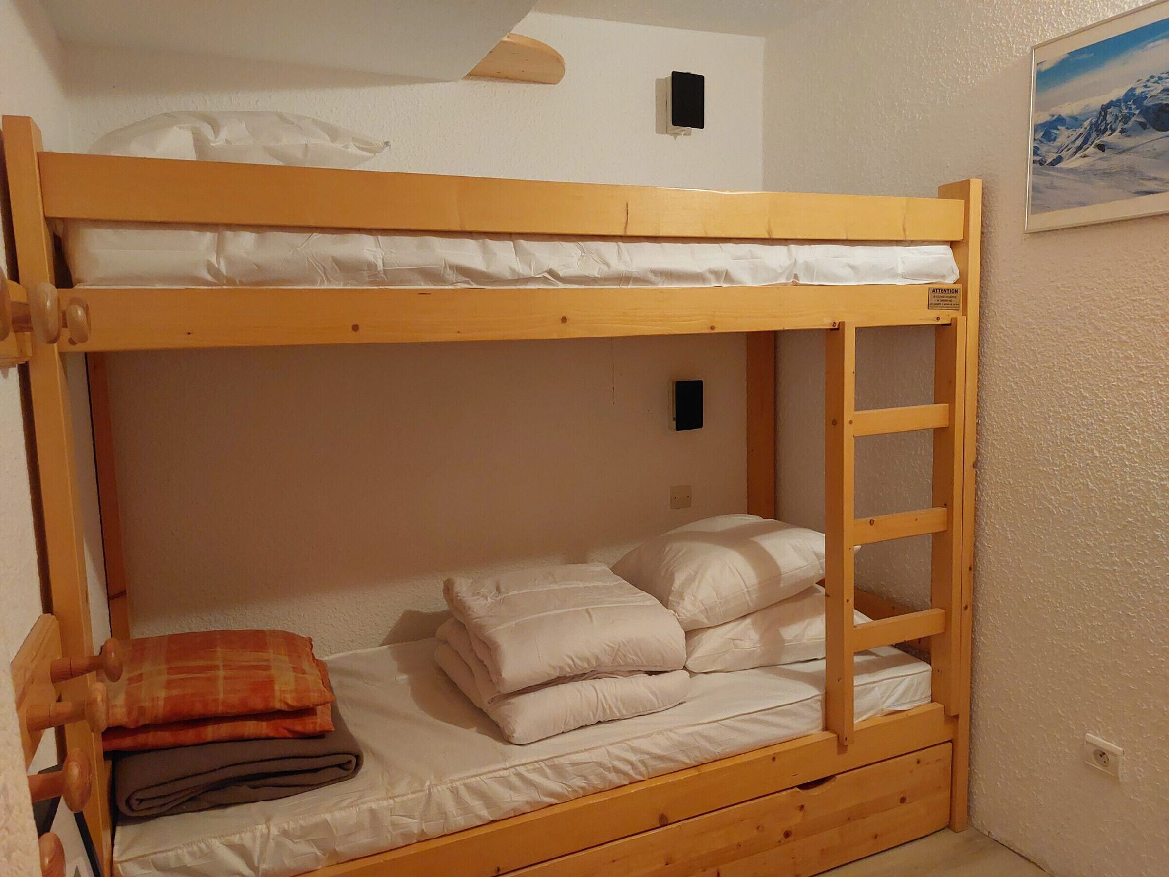 A bunk bed with a ladder, a folded blanket, and a pillow on the lower bunk.