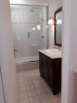 A bathroom with a glass-enclosed shower, a white sink, dark wooden cabinets, and a mirror with wall-mounted lights. - Homerez - House near Chanteloup. (Le Pont Cagnon Chanteloup)