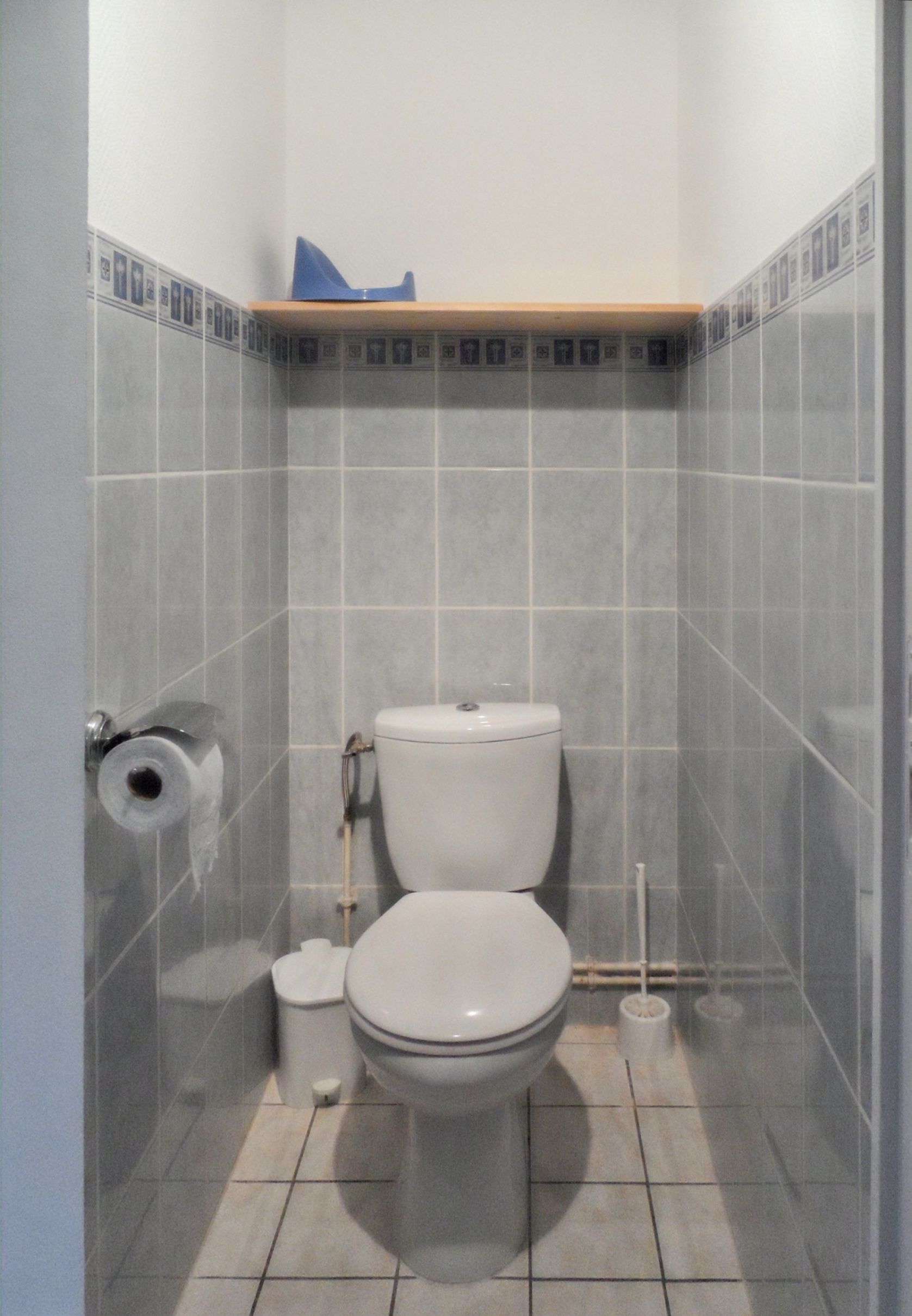 A small, tiled bathroom with a toilet, a bidet, and a toilet paper holder.
