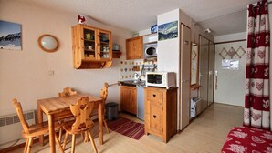 A compact kitchen with wooden cabinets, a microwave, and a toaster. There's a dining table with chairs and a small rug. - STUDIO - APARTMENT -SKI IN SKI OUT -SAINT JEAN D'AULPS SKI RESORT - 4 PEOPLE (Saint-Jean-d´Aulps)