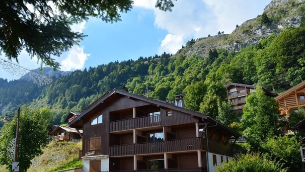 Eine mehrstöckige Holzhütte mit Balkonen vor einer Bergkulisse.