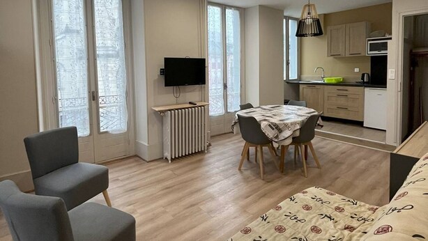 A modern apartment with a dining area, kitchen, and a TV mounted on the wall. - T2 Apartment for 5 in Cauterets (Cauterets)