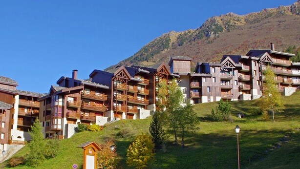 A row of wooden multi-story buildings with balconies, set against a mountainous backdrop. - 2-room apartment in Valmorel with balcony and ski locker (Valmorel)