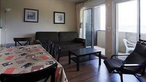 Un salon comprenant un canapé, une table à manger avec des chaises, une table basse et un balcon également équipé de chaises.