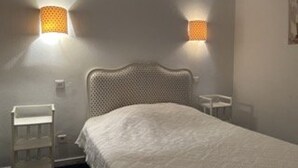 A bedroom with a bed, two wall-mounted lamps, a chair, and a small table. - 6-sleeper apartment in Banyuls-sur-Mer, air conditioning, parking (Banyuls-sur-Mer)