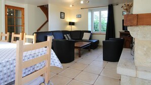 Een gezellige woonkamer met een bank, stoelen, een eettafel en een trap.