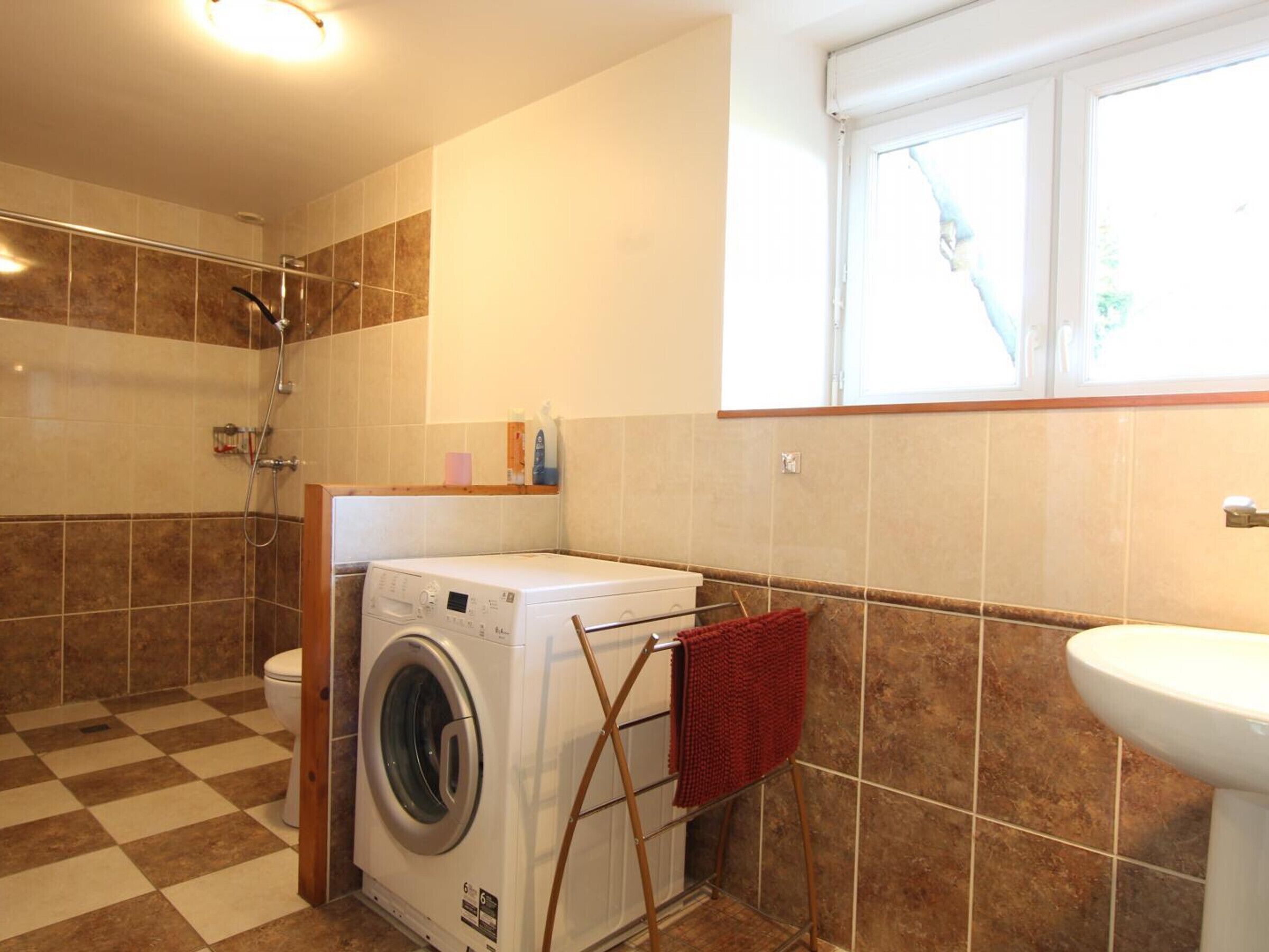 Een badkamer met een wasmachine, douche en wastafel.