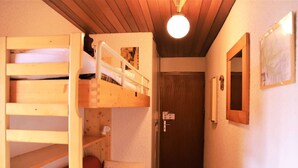 Une pièce avec des lits superposés, une porte et un miroir fixé au mur.