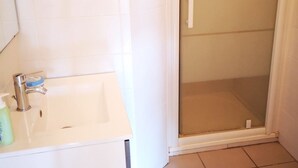 Un baño con lavabo blanco, espejo y zona de ducha.